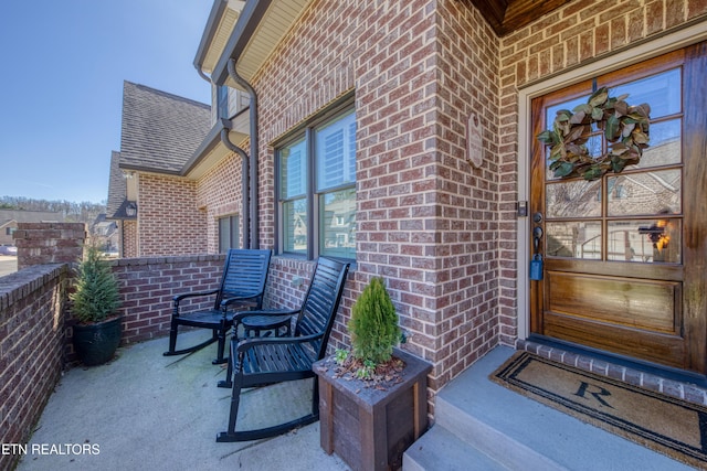 entrance to property with brick siding and roof with shingles