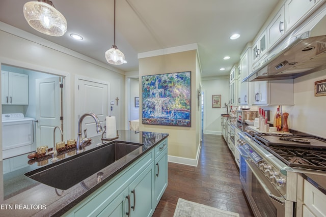 kitchen with stainless steel stove, hanging light fixtures, a sink, dark stone countertops, and washer / dryer