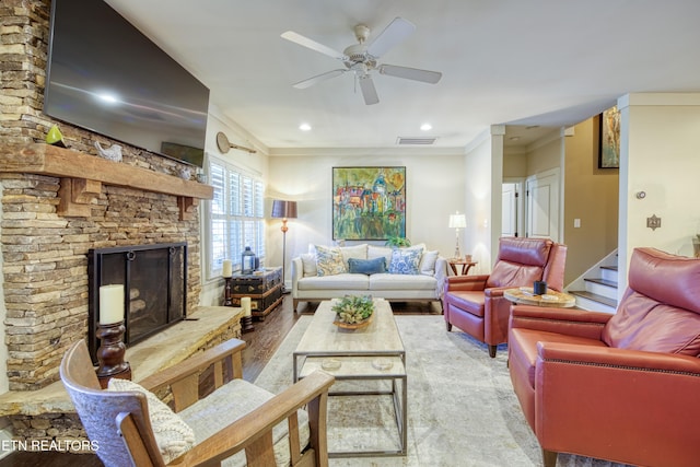 living room with ceiling fan, a stone fireplace, recessed lighting, visible vents, and crown molding