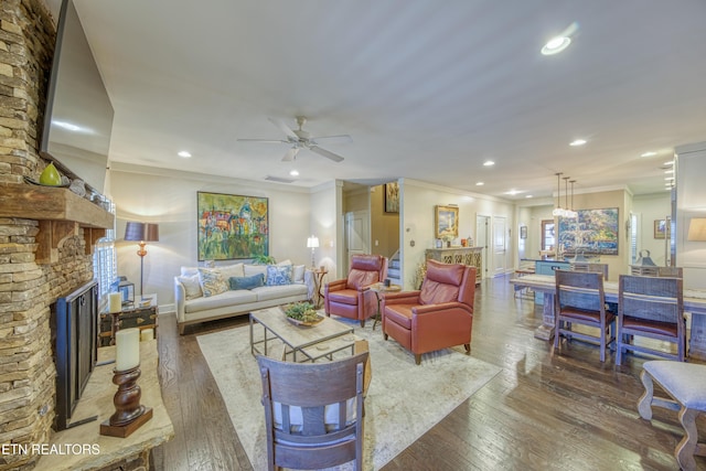 living area featuring hardwood / wood-style flooring, a large fireplace, crown molding, and recessed lighting