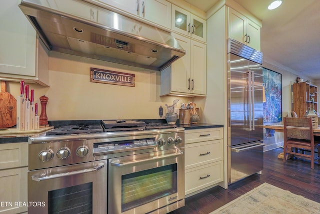 kitchen with dark wood-style flooring, dark countertops, glass insert cabinets, high quality appliances, and under cabinet range hood