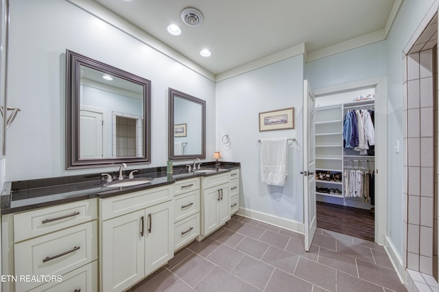 full bathroom with double vanity, tile patterned flooring, visible vents, and a sink