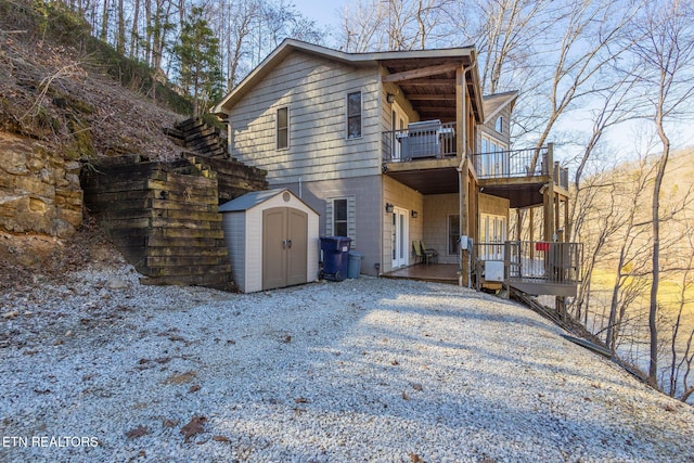 exterior space with an outbuilding, cooling unit, a balcony, and a shed