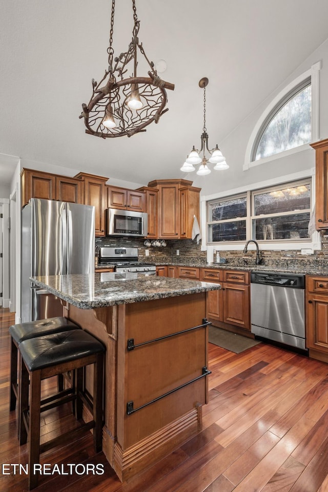 kitchen featuring hardwood / wood-style flooring, appliances with stainless steel finishes, decorative backsplash, and a center island