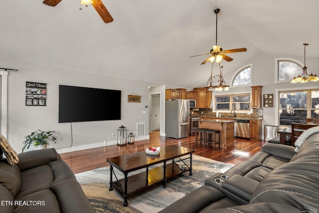 living area featuring dark wood finished floors, visible vents, a ceiling fan, high vaulted ceiling, and baseboards