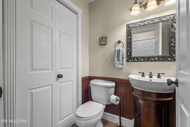 bathroom featuring wood walls, wainscoting, vanity, and toilet