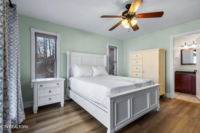 bedroom featuring a ceiling fan, baseboards, wood finished floors, and ensuite bathroom