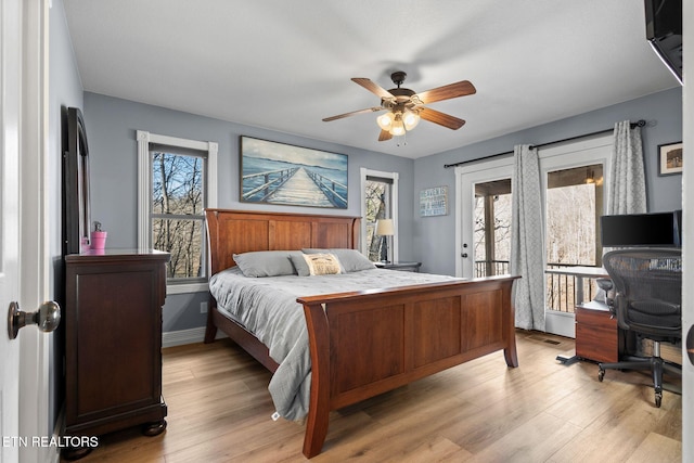 bedroom featuring access to exterior, multiple windows, light wood-style floors, and ceiling fan