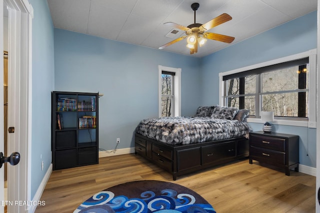 bedroom featuring baseboards, ceiling fan, visible vents, and light wood finished floors