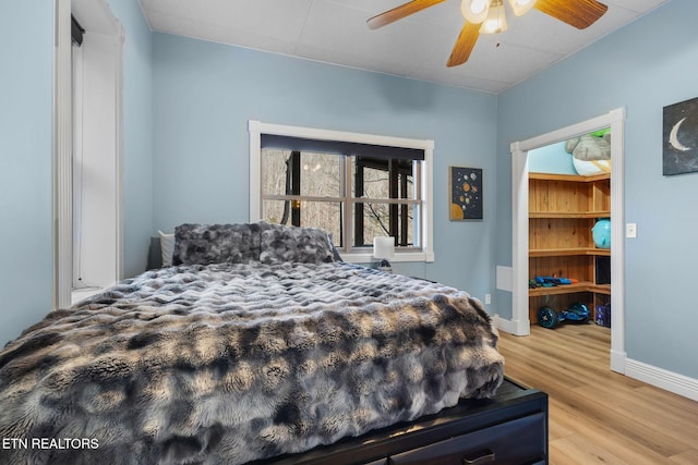 bedroom featuring a ceiling fan, baseboards, and wood finished floors