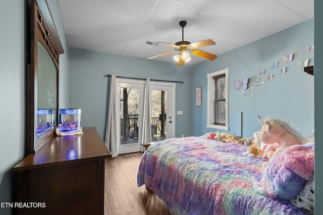 bedroom featuring light wood-type flooring, access to outside, visible vents, and a ceiling fan