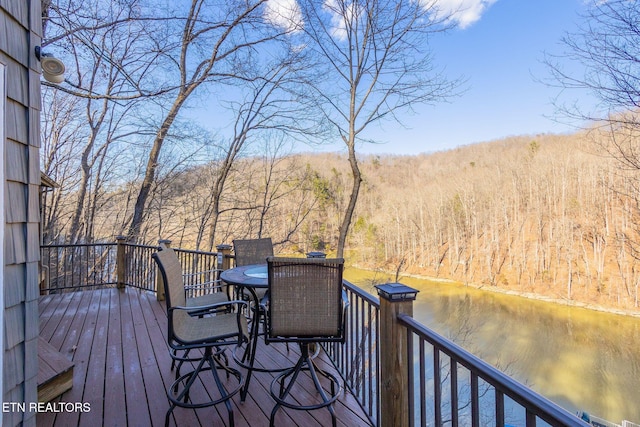 wooden deck featuring outdoor dining space and a forest view