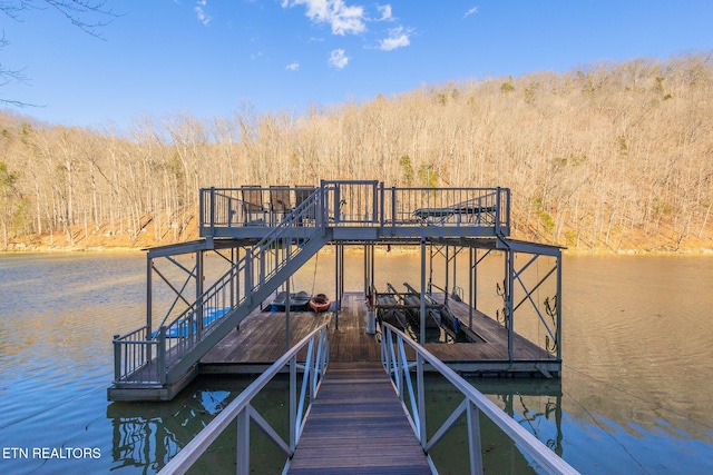 view of dock with a water view and a forest view