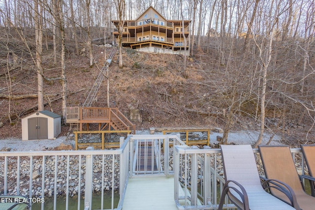 rear view of house with stairs, a shed, an outdoor structure, and a wooden deck