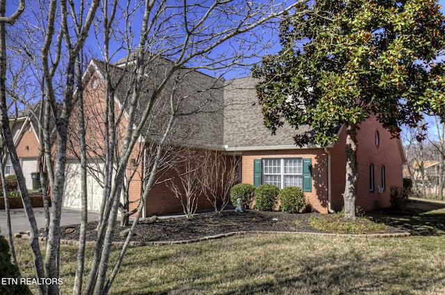 view of front facade featuring a shingled roof, a front yard, and brick siding