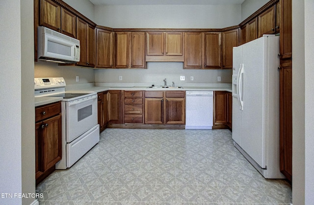 kitchen with white appliances, brown cabinets, light countertops, light floors, and a sink