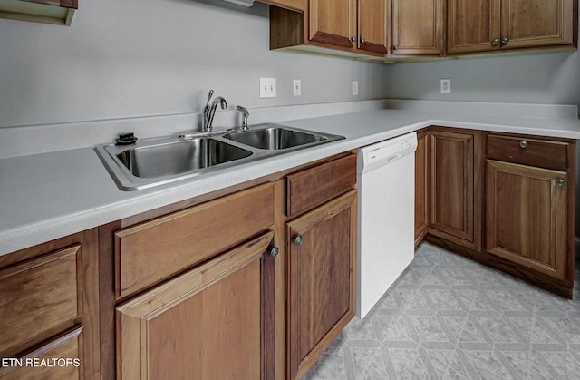 kitchen with light floors, white dishwasher, light countertops, and a sink