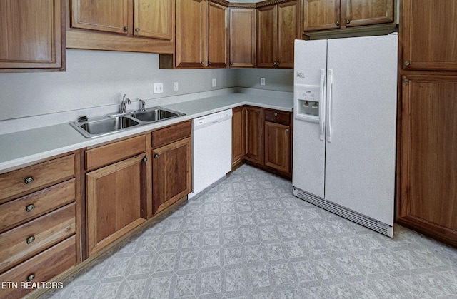 kitchen with white appliances, brown cabinets, light countertops, light floors, and a sink