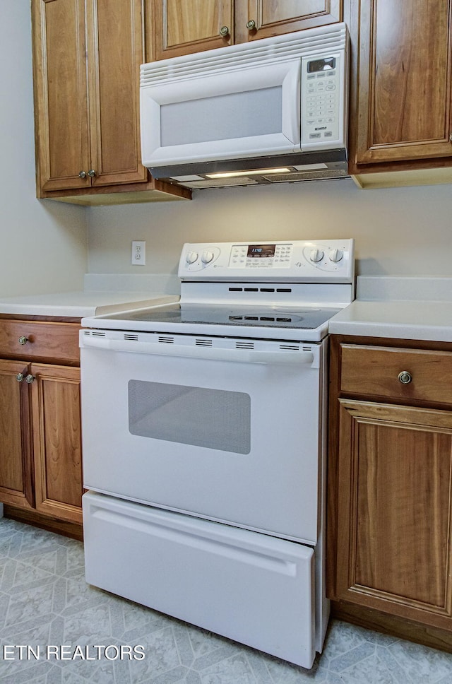 kitchen with white appliances, brown cabinets, and light countertops