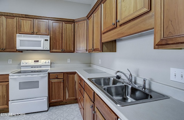 kitchen featuring white appliances, a sink, light countertops, brown cabinets, and light floors