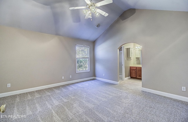 interior space featuring arched walkways, a ceiling fan, light carpet, high vaulted ceiling, and baseboards