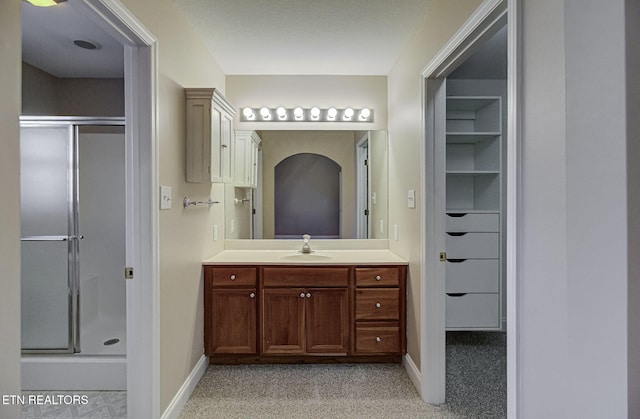 full bath featuring a stall shower, vanity, and baseboards