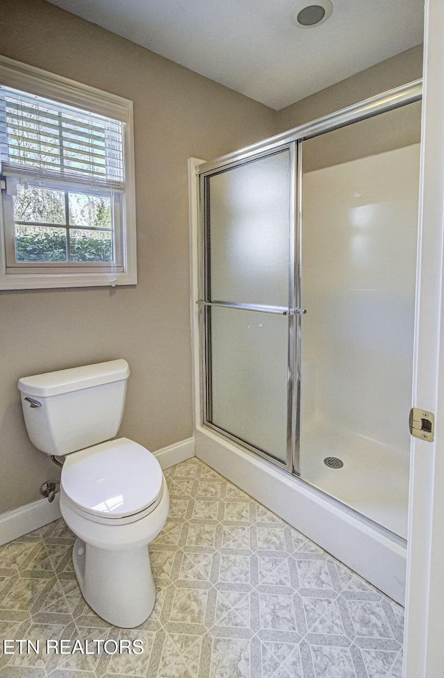 full bathroom featuring toilet, a shower stall, and baseboards