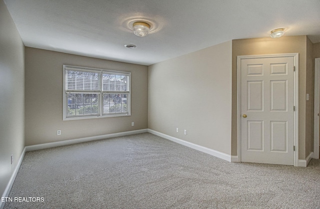 spare room featuring carpet floors, visible vents, and baseboards