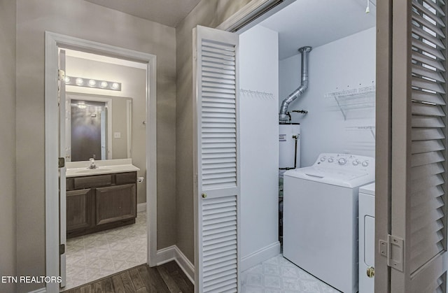 clothes washing area with a sink, laundry area, washing machine and clothes dryer, and tile patterned floors