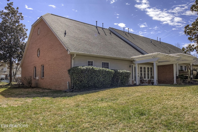 rear view of house featuring a shingled roof, brick siding, a yard, and a pergola