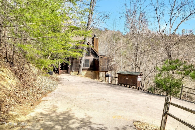 view of side of home with a chimney, log siding, and fence