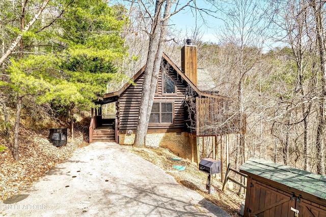 view of side of property with a chimney and log siding