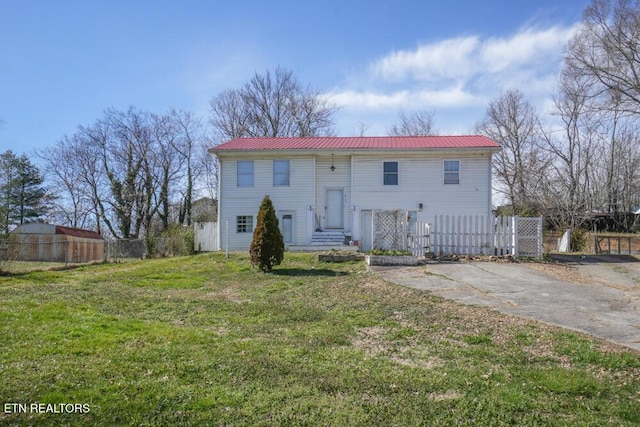 bi-level home featuring metal roof, a front yard, and fence