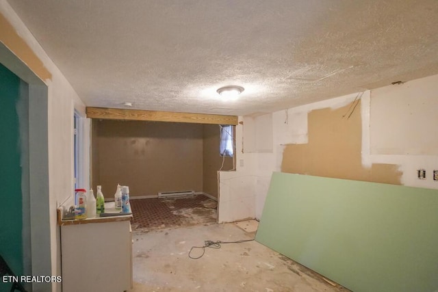 interior space featuring a baseboard heating unit, a textured ceiling, and unfinished concrete flooring