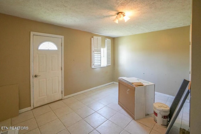 foyer featuring light tile patterned flooring, a textured ceiling, and baseboards