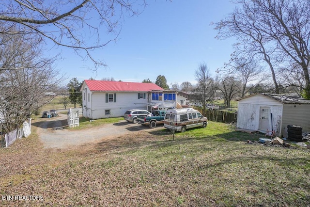 rear view of property with a yard, crawl space, fence, metal roof, and an outdoor structure