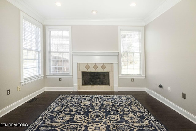 living area featuring dark wood-style floors, a healthy amount of sunlight, a tile fireplace, and crown molding