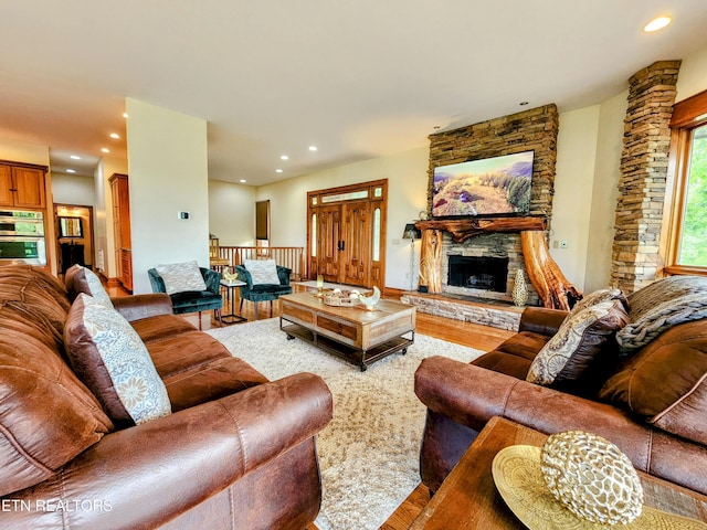 living room with recessed lighting, wood finished floors, and a stone fireplace