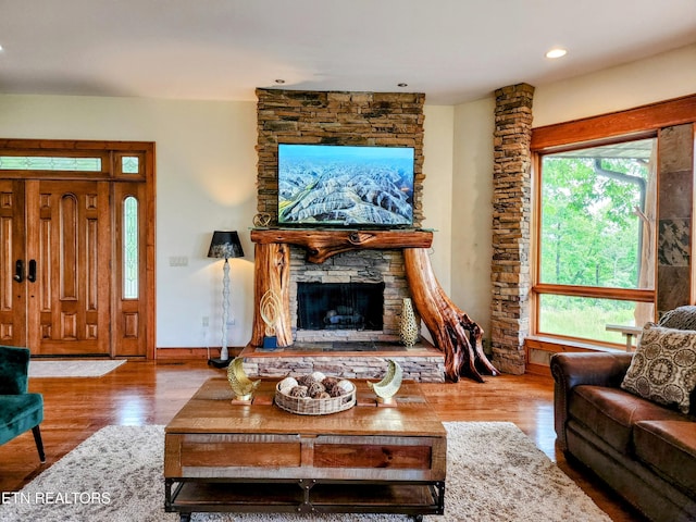 living area featuring recessed lighting, baseboards, wood finished floors, and a stone fireplace