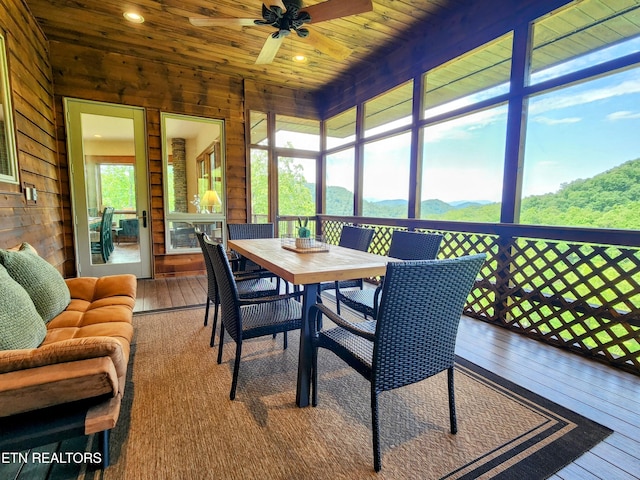 sunroom with wooden ceiling, a mountain view, and a ceiling fan