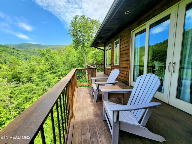 wooden terrace with a view of trees and french doors