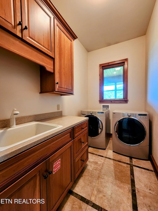 clothes washing area with baseboards, a sink, cabinet space, and washer and dryer