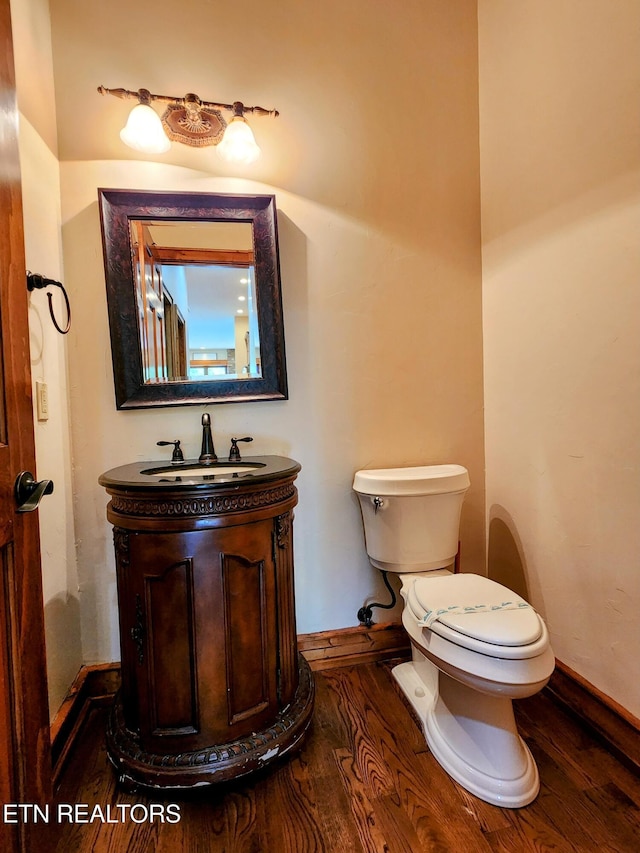 bathroom with baseboards, vanity, toilet, and wood finished floors