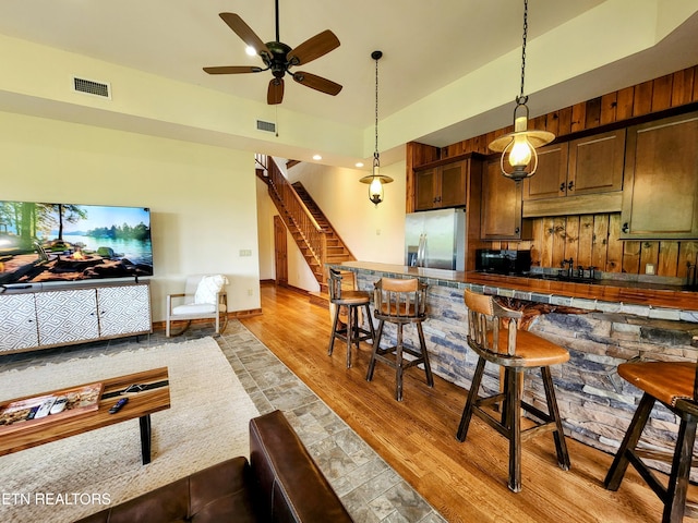 kitchen featuring visible vents, dark countertops, light wood-style flooring, black appliances, and a kitchen bar