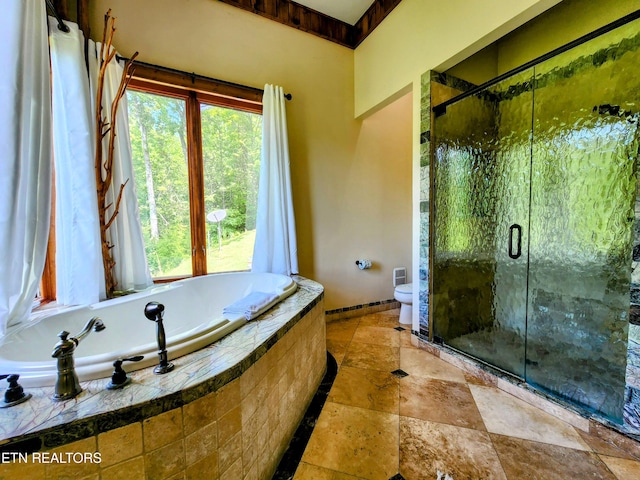 bathroom featuring a stall shower, baseboards, toilet, stone tile flooring, and a bath