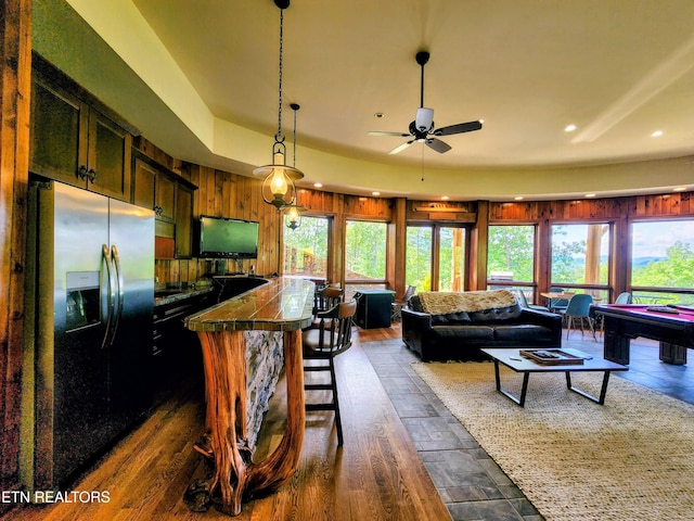 kitchen featuring stainless steel fridge, tile counters, a breakfast bar area, a center island, and pendant lighting