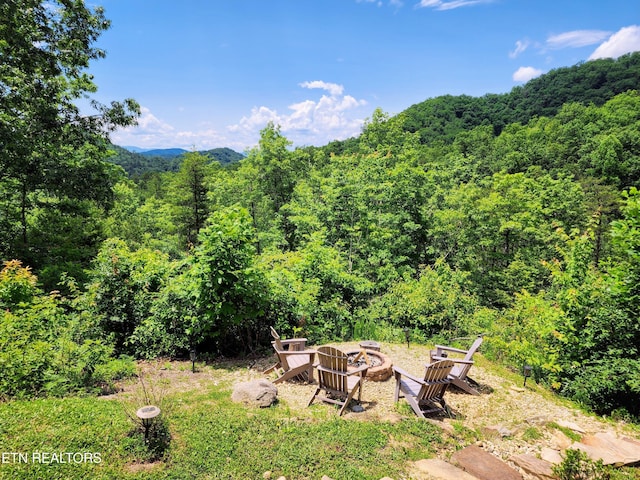 view of yard featuring an outdoor fire pit and a forest view