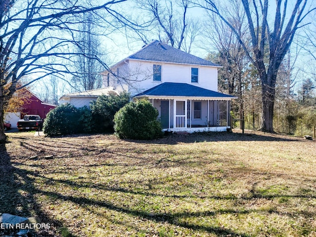 view of front facade featuring a shingled roof, a front yard, and a sunroom