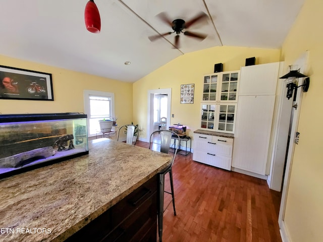 kitchen featuring dark wood finished floors, ceiling fan, glass insert cabinets, vaulted ceiling, and white cabinetry