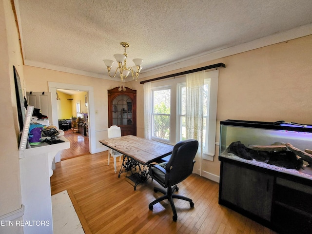 office featuring an inviting chandelier, light wood-style flooring, crown molding, and a textured ceiling